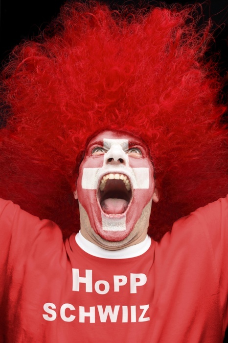 Swiss supporter man shouting Screaming young man, football fan with a painted face, Swiss national flag, wearing a red t shirt, lettering  Hopp Schwiiz , German for  Go Switzerland 