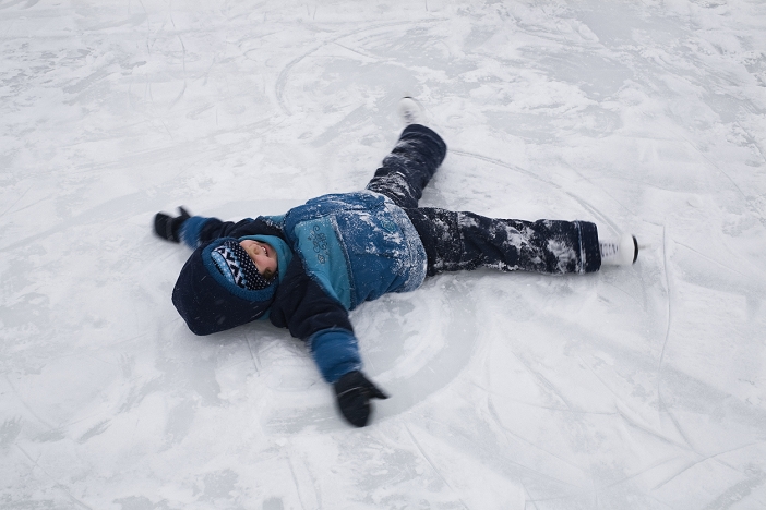 Boy lying on snow Child making snow angel
