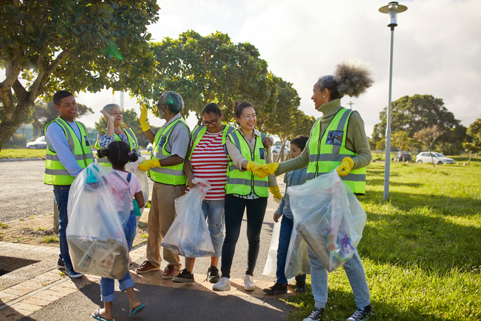 Happy volunteers celebrating, cleaning litter from sunny park