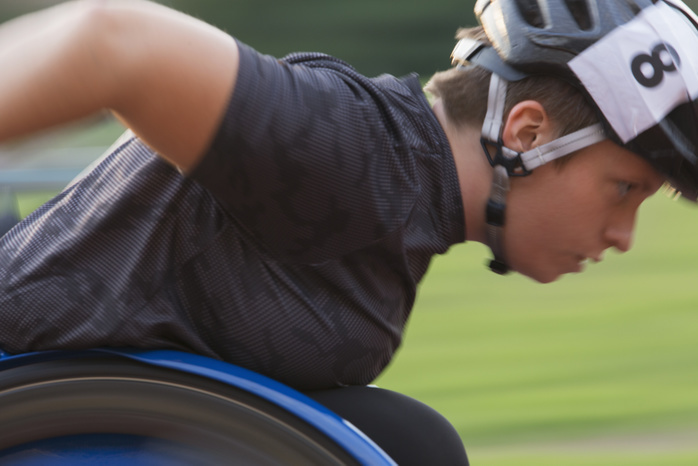 Wheelchair Athletics Determined female paraplegic athlete speeding along sports track during wheelchair race