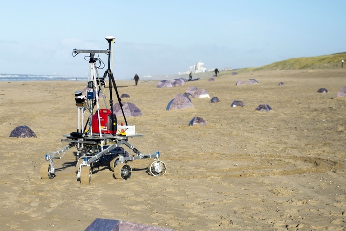 Martian rover tests on sandy beach This image may not be used to state or imply ESA endorsement of any company or product   Martian rover tests on sandy beach. Rover navigation software being tested with 212 cardboard  rocks  on a sandy beach. This test is being conducted by the European Space Agency  ESA  s Networking Partnering Initiative and Planetary Robotics Laboratory. One software programme matches landmarks on the ground to images acquired from orbit  here, using an overhead drone . The other software programme applies lidar  the laser equivalent of radar  to help track the rover s motion. Photographed on 26 November 2015, at Katwijk beach, close to ESA s ESTEC technical centre in the Netherlands. Photo by EUROPEAN SPACE AGENCY G. Porter, CC BY NC ND IGO 3.0 SCIENCE PHOTO LIBRARY