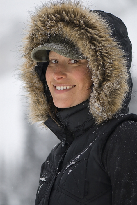 A young woman smiles at the camera wearing a furry hood.