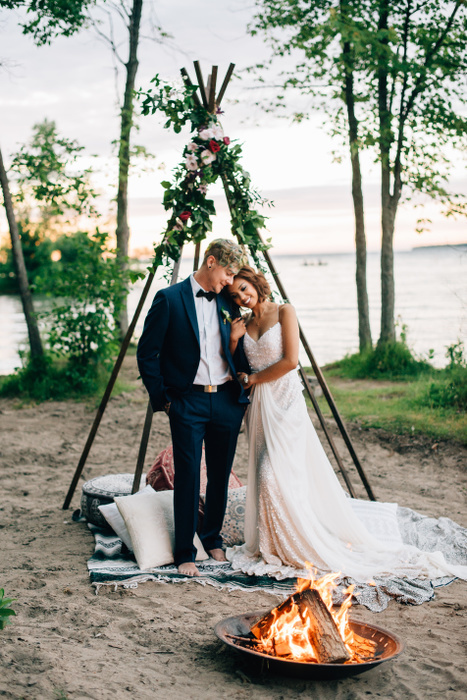 Bride and groom standing by lakeside campfire, Lake Ontario, Toronto, Canada