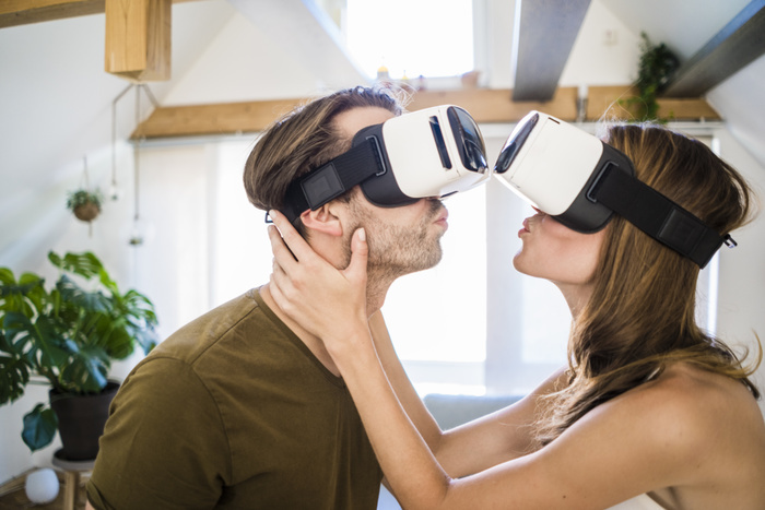 Couple wearing VR glasses kissing at home