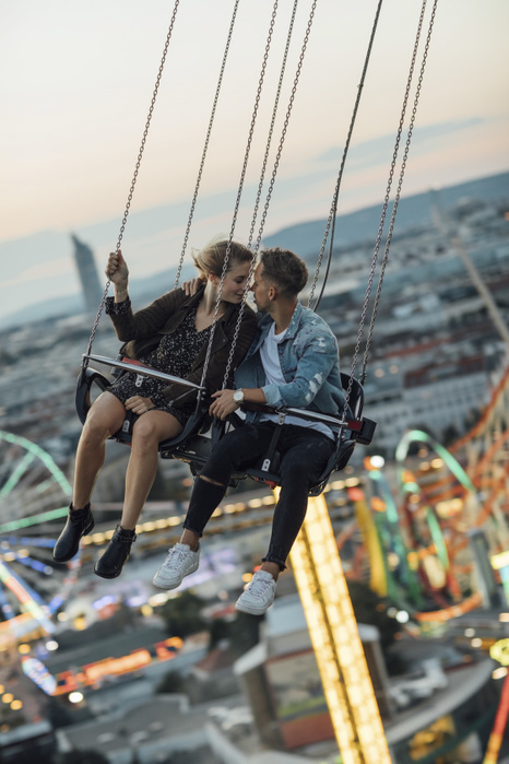 Young couple in love, riding chairoplane on a fairground Young couple in love, riding chairoplane on a fairground