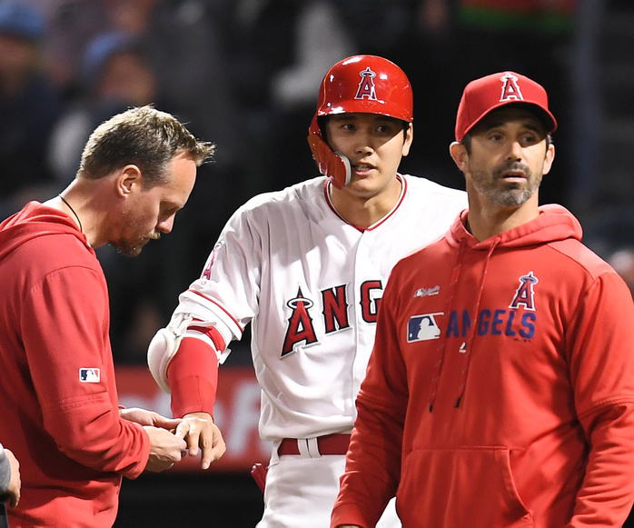 2019 MLB Otani: Ball hits right hand Los Angeles Angels designated hitter Shohei Ohtani is checked by team athletic trainer Adam Nevala  L  after getting hit by a pitch on his right ring finger while striking out in the eighth inning during the Major League Baseball game against the Minnesota Twins at Angel Stadium in Anaheim, California, United States, May 20, 2019.  Photo by AFLO 