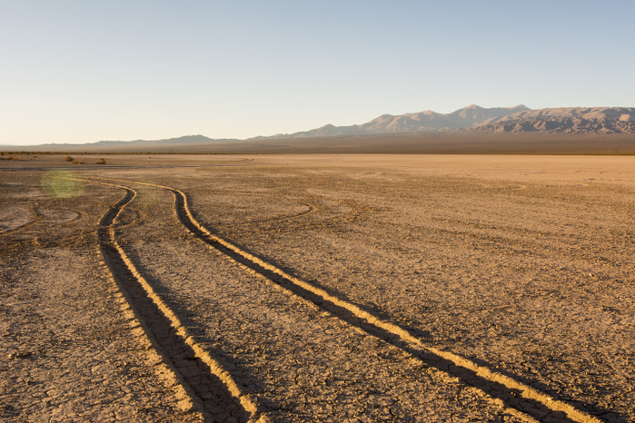 Argentina Tire tracks through a dry lake bed lead the eye to wards a mountain range at dawn  Barreal, San Juan, Argentina