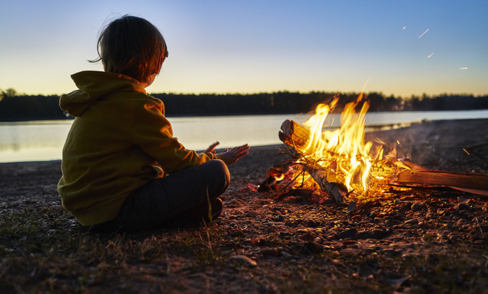Argentina, Patagonia, Concordia, boy sitting at camp fire at a lake Argentina, Patagonia, Concordia, boy sitting at camp fire at a lake