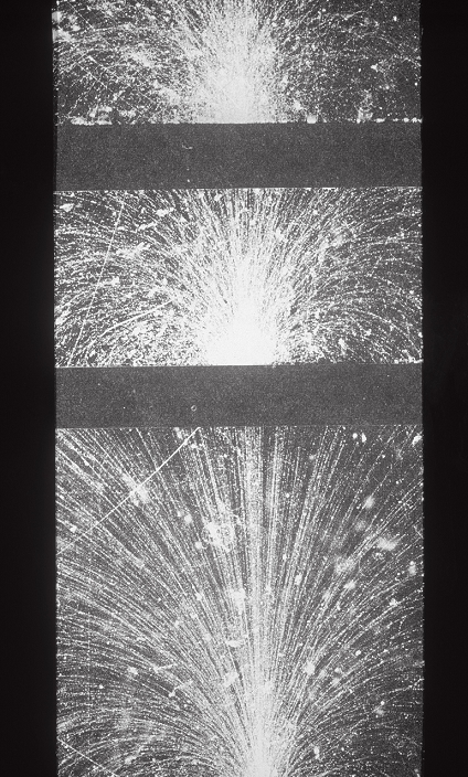 Cloud chamber photo of a 'shower' of electrons & positrons produced by a cosmic ray. The primary cosmic rays are atomic nuclei which collide with atoms in the upper atmosphere. A common product of these collisions is the neutral pion, which rapidly decays into pairs of gamma rays. In this picture, one of these gamma-rays initiates the cascade of electron-positron pairs at the top of the chamber. The electrons & positrons curve in different directions in the chamber's magnetic field. They also produce more gamma rays, through radiation & annihilation; when these interact with two horizontal sheets of lead (black) the process repeats itself, regenerating the shower each time.
