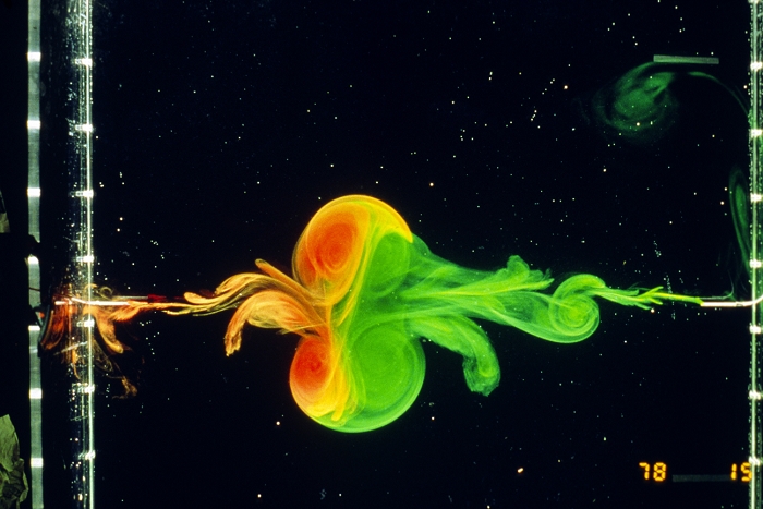 Chaotic systems: head-on collison of two dipolar vortices in a stratified fluid environment. The original vortices, dyed orange and green, have exchanged a partner to form two new (mixed) dipoles which are moving at roughly right angles to the original direction of travel, that is, towards the top & bottom of the image. The green fluid was injected from the right, the orange from the left. Dipolar vortices are relevant to turbulence in large-scale geophysical systems such as the atmosphere or oceans. Turbulence in fluid systems is one example of a chaotic system.