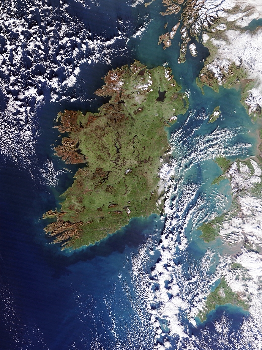 Ireland, true-colour satellite image. North is at top. Vegetation is green, barren land is brown and water is blue. Clouds (white) are seen at top left over the Atlantic Ocean, and over the Irish Sea at lower right. Snow and ice (white) are seen on the mountains of Scotland (upper right) and of Wales (lower right) on the western coast of mainland UK. Ireland is mostly free of ice due to the warming influence of the Gulf Stream. Rugged mountains and cliffs (brown) line the western coast of Ireland, while lakes and peat bogs dot the interior. Lough Neagh, Northern Ireland, is the large lake in the island's north. Photographed on 4 January 2003 by the MODIS sensor on NASA's Terra satellite.