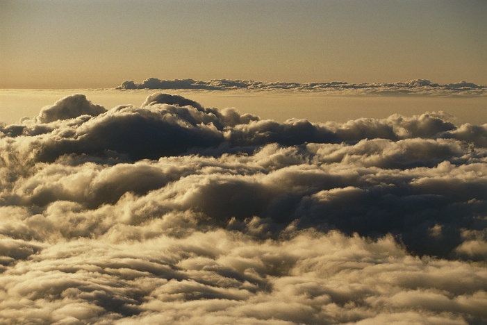 Cloud tops over Hawaii. View over the tops of cloud banks, photographed from the peak of Mauna Kea, Hawaii, near sunset. Two large banks of nimbostratus clouds are seen - one in the foreground and one on the horizon. Between these is a flat, hazy veil of altostratus.