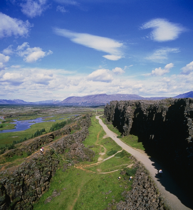 The meeting of the North American tectonic plate & the European tectonic plate can be clearly seen near Pingvellir, Iceland, where ravines & cliffs mark the line of the Atlantic Fault. To the left of the picture is the eastern edge of the north American continental plate, to the right the western edge of Europe. The Atlantic Fault cuts across Iceland from north-east (in the distance) to south-west. The two plates are slowly moving apart by the process of continental drift, as the Atlantic widens. This process causes Iceland's intense seismic & volcanic activity. The last major earthquake occurred at Pingvellir in 1789, when part of the land sank by 50cm in 10 days.