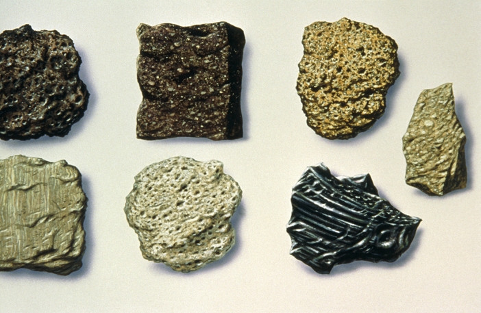 Illustration depicting different types of rock, all of which are of volcanic origin. They are (clockwise from top left): vesicular basalt, andesite, tuff, ignimbrite, obsidian, pumice and rhyolite.