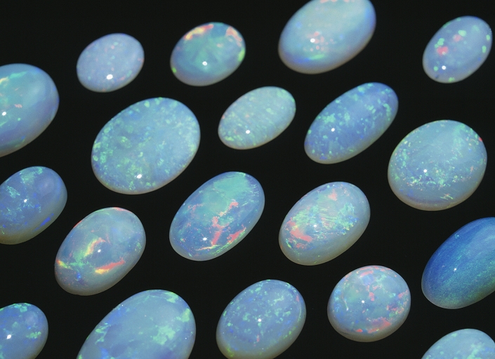 Opal gemstones. This mineral is a form of hydrous silicon oxide (silica, SiO2). It is named after the Indian word for precious stone. After it has been cut and polished, it has an iridescent sheen. This is as a result of its composition of microspheroids of silicon oxide that refract light. This is enhanced by reflections from tiny conchoidal fractures (crazing) that occur on exposure to the air. Opal never occurs in a crystalline form, but as small veins, globules and crusts. Several types occur: hazy blue, milky white, colourless and the highly prized red (fire opal) and black.