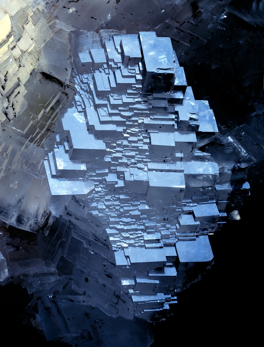 Calcite crystals reflecting a blue sky. These are parallel planes of rhombic crystals. Calcite is a very common mineral form of calcium carbonate that is prized by rock collectors for its beauty.
