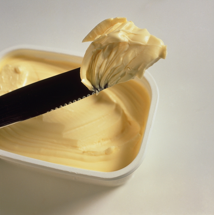 Margarine. Knife scoops margarine from a plastic tub. Margarine is a butter-substitute that does not contain dairy fat, but is usually made from vegetable oils and skimmed milk. It may also contain vitamin A and D supplements. Margarine is used as an ingredient in food recipes and in cooking. Margarine that is high in polyunsaturated fat is a healthy alternative to butters containing saturated fat. Saturated fat affects blood cholesterol and contributes to heart disease.