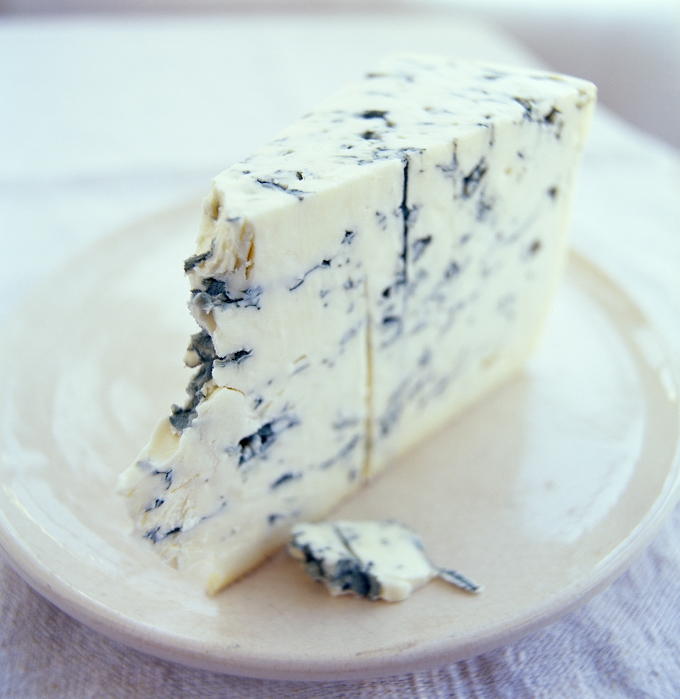 Roquefort cheese on a plate. Roquefort cheese is a French cheese originating from the Roquefort-sur- Soulzon region. It is made from cow's milk and it is ripened in limestone caves using the mould Penicillium roquefortii to produce the blue-green marbling. This is a blue-coloured variety. Cheeses are a good source of calcium, but contain high levels of fat.