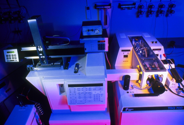 Forensic drug detection apparatus. A gas chromatography machine (left) connected to a mass spectrometer (right) in a forensic laboratory. This equipment is sensitive enough to detect minute quantities of illegal drugs in the hair of a suspect - weeks after any drugs were taken. A sample injection robot (left) transfers samples from small vials to the chromatography machine, where the samples are evaporated and separated according to molecular weight. The spectrometer identifies even minute traces of chemicals as they emerge from the chromatography tube (not visible).
