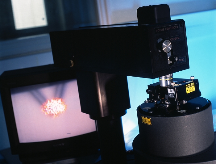 Atomic force microscope. Television screen (left) displaying a specimen being analysed by an atomic force microscope (AFM, right). AFMs are tools for studying the surfaces of objects at an atomic level. They work by holding an extremely fine 'stylus' (usually a diamond crystal) in contact with the sample, and slowly moving it across its surface. The stylus is spring-loaded, and its deflection is detected and can be converted into a computer map of the surface. The AFM is similar in principle to the scanning tunnelling microscope (STM), but has the advantage that the subjects to be studied do not have to conduct electricity.