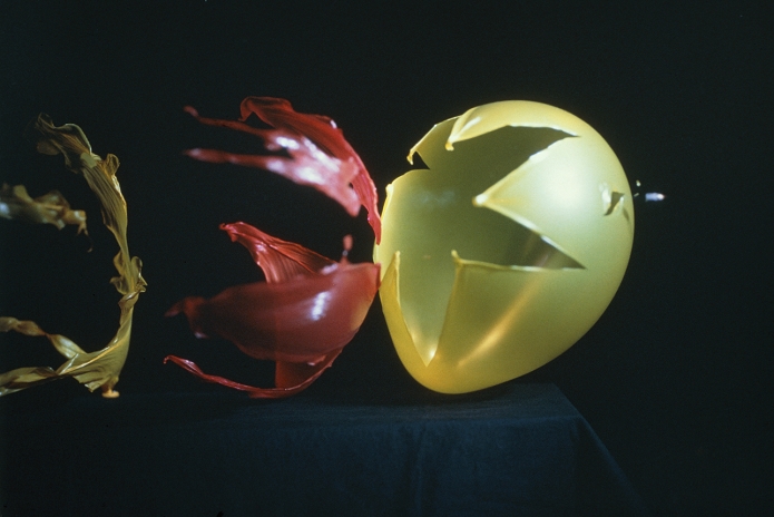High-speed photograph of 3 balloons being burst by a bullet; the projectile is travelling from left to right.