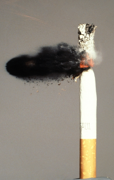 High speed photograph of a . 22 calibre bullet striking a burning cigarette. The bullet, emerging in a cloud of charred tobacco fragments, is travelling at about 450 metres per second (Mach 1.4).