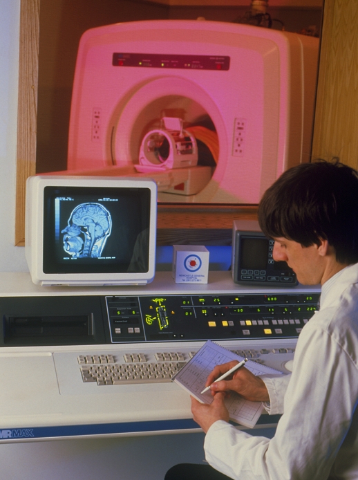 . Man undergoing a magnetic resonance imaging (MRI) brain scan, showing the radiographer at the control panel in foreground, with the subject lying through the coils of the scanner's magnets visible through the window. MRI is a diagnostic technique that provides revealing imagery of tissues & organs within the body. It is of special value in resolving the nervous tissue of the brain and spinal cord & in locating related diseases. Here, a mid-sagittal image of the (normal) subject's brain appears on the display at left. Features visible include the spinal cord and grey & white matter of the brain. MODEL RELEASED