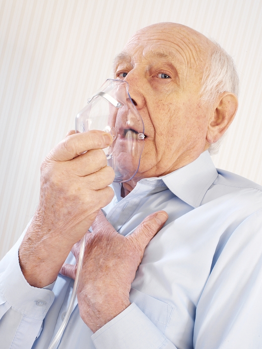 . Breathing difficulties. 78 year old man using an oxygen mask for the treatment of breathing difficulties. The face mask provides oxygen-enriched air to treat hypoxia (inadequate oxygen in the body tissues), which can be caused by lung and breathing disorders such as asthma, emphysema and chronic bronchitis. MODEL RELEASED