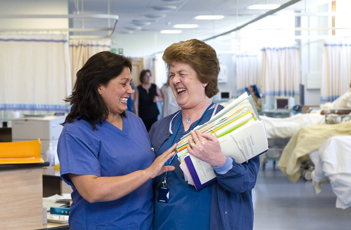 . Nurses laughing together on a hospital ward. Photographed in the UK. MODEL RELEASED