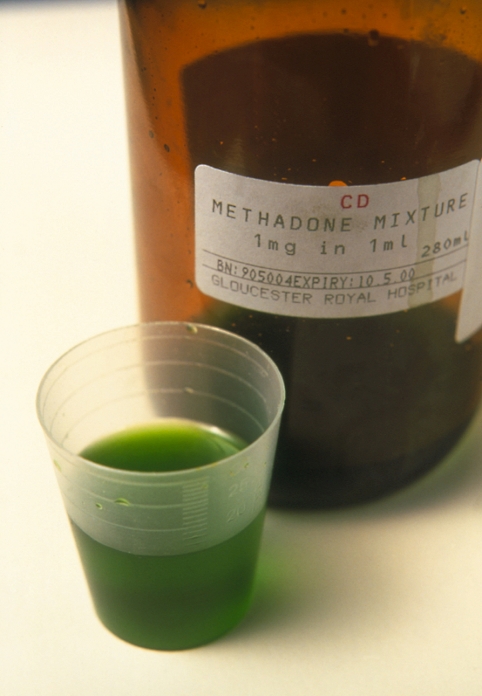 Methadone. Bottle containing the drug methadone and a measure of the drug in a beaker. Methadone is opiate analgesic that can be substituted for opioid drugs such as heroin (diamorphine). The methadone drug mimics the effects of drugs like heroin and so helps to combat withdrawal symptoms. When a drug addict is treated with methadone the dose must gradually be reduced with time as methadone itself is highly addictive.