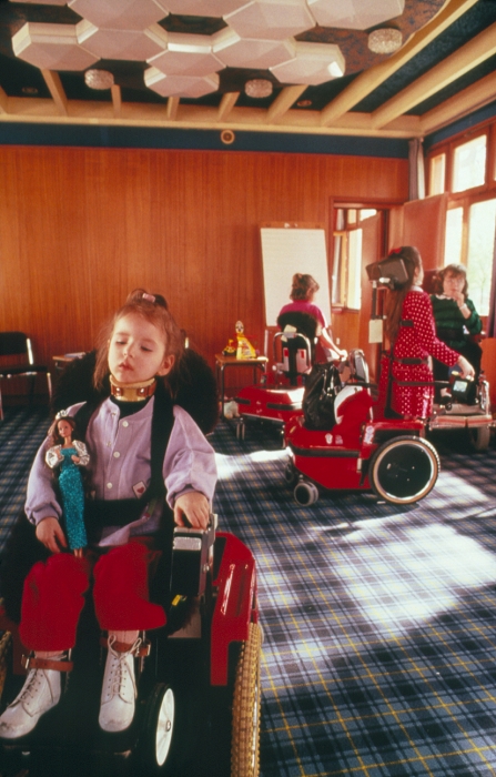 Muscular dystrophy. Support centre for child sufferers of muscular dystrophy. Here, children use specially adapted wheelchairs for movement, to compliment various therapies like walking, and to support the body. The girl in the foreground wears a neck brace and is strapped securely into her chair. Muscular dystrophy is an inherited muscle disorder of unknown cause in which there is slow but progressive degeneration of muscle fibres. Many forms occur and no curative treatment is known. Affected children should keep as active as possible to maintain use of muscles not yet dystrophic. Photographed at 'Association Francais de Myopathie (AFM)' in France.