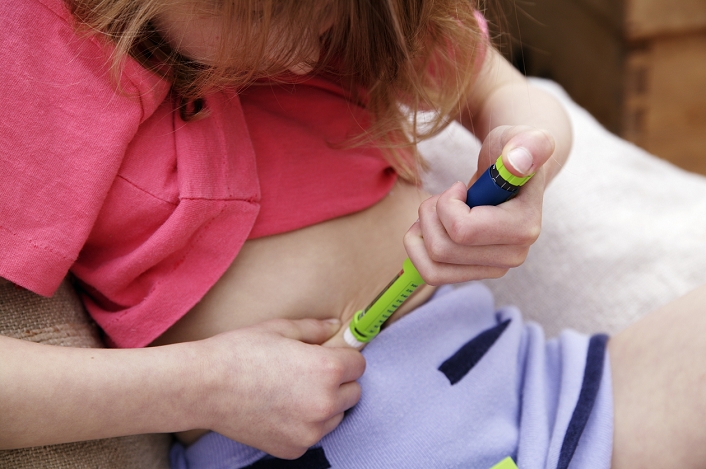 Insulin injection. Diabetic girl injecting herself in the abdomen with insulin. She has diabetes mellitus. This is a disorder affecting glucose sugar metabolism, where sugar is not oxidised due to a lack of the pancreatic hormone insulin. Unused sugar accumulates in the blood and the urine. Fats are utilised as an alternative energy source, which leads to a build-up of ketones in the blood that may eventually cause convulsions and diabetic coma. Treatment is based on a strict diet and the use of daily insulin injections to maintain the blood-sugar balance. This injector is a Novopen Junior from Novo Nordisk.