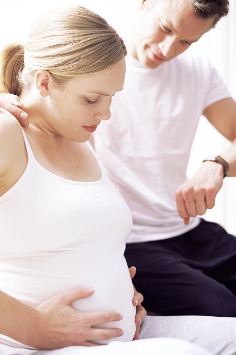 . Timing contractions. Man supporting his pregnant partner and measure the time between contractions. Uterine contractions in the early stages of pregnancy are spasms of rythmic, squeezing muscular activity in the uterus wall. They increase in strength and frequency from the first stage of labour. MODEL RELEASED