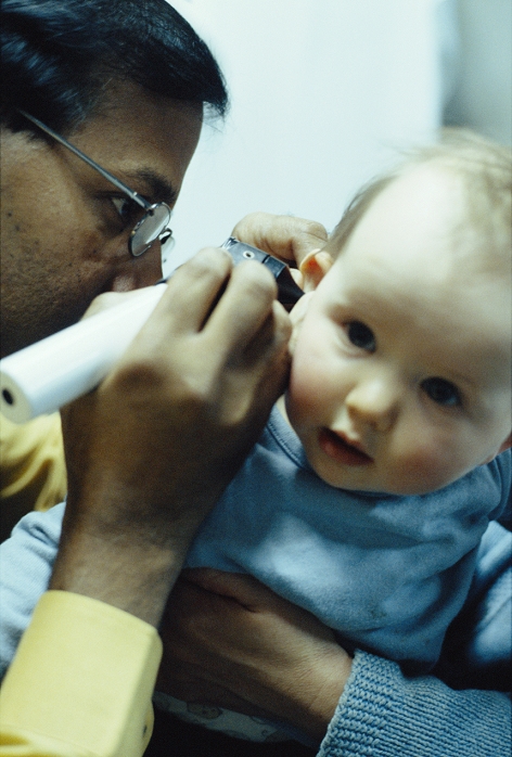 . Otoscopy examination. Doctor using an otoscope to examine the external auditory canal in the ear of a baby. The otoscope comprises a handle, which contains a power source; the head, which contains a light bulb and a magnifying lens; and the cone, which is inserted into the ear canal. The doctor uses this instrument to check the health of the ear canal and the ear drum (tympanic membrane). Most otoscopes have small air vents through which the doctor can puff air. This process, called insufflation, allows the doctor to see whether the eardrum moves correctly. Abnormal findings of otoscopy may include eczema, inflammation, excess wax or a foreign object. MODEL RELEASED