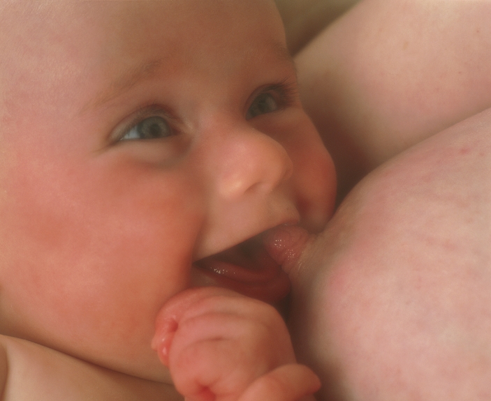 . Breast-feeding. Close-up of a smiling four month old baby girl feeding from her mother's breast. Human milk contains an ideal balance of nutrients, as well as antibodies that protect the baby against infection. Breast- feeding also provides the mother and child with a physical closeness that strengthens the bond between them. MODEL RELEASED