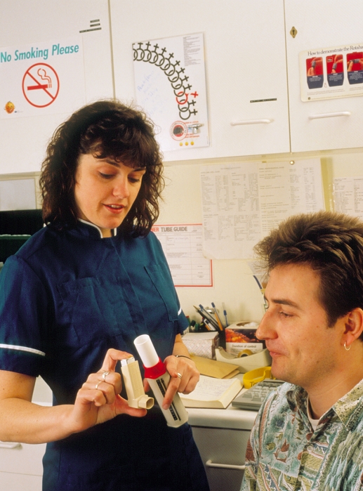. Nurse demonstrating the use of a Becotide inhaler (left) and a peak flow meter (right) to a young male patient with asthma. The inhaler contains the corticosteroid drug beclomethasone dipropionate. The action of corticosteroids in asthma is not fully understood, but it is believed they give relief by reducing inflammation in the bronchial mucous membrane, causing less oedema (fluid retention) and hypersecretion of mucous. The peak flow meter is used to assess respiratory capacity by measuring 'peak flow', the maximum flow of exhaled air expressed in litres per minute. MODEL RELEASED