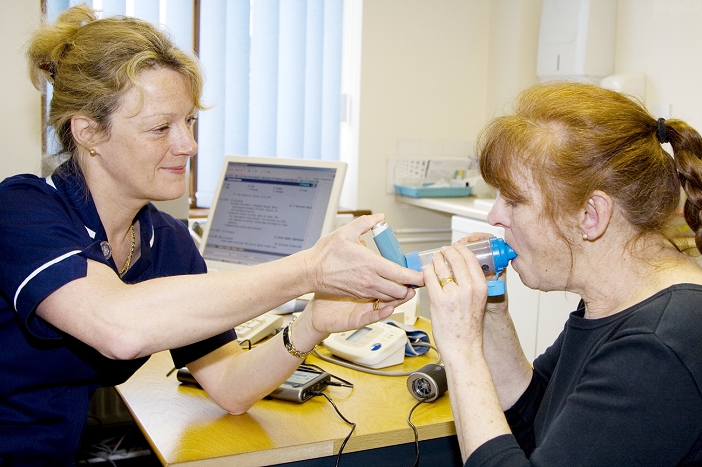 . Asthma consultation. Nurse teaching a patient how to take asthma medication correctly. MODEL RELEASED