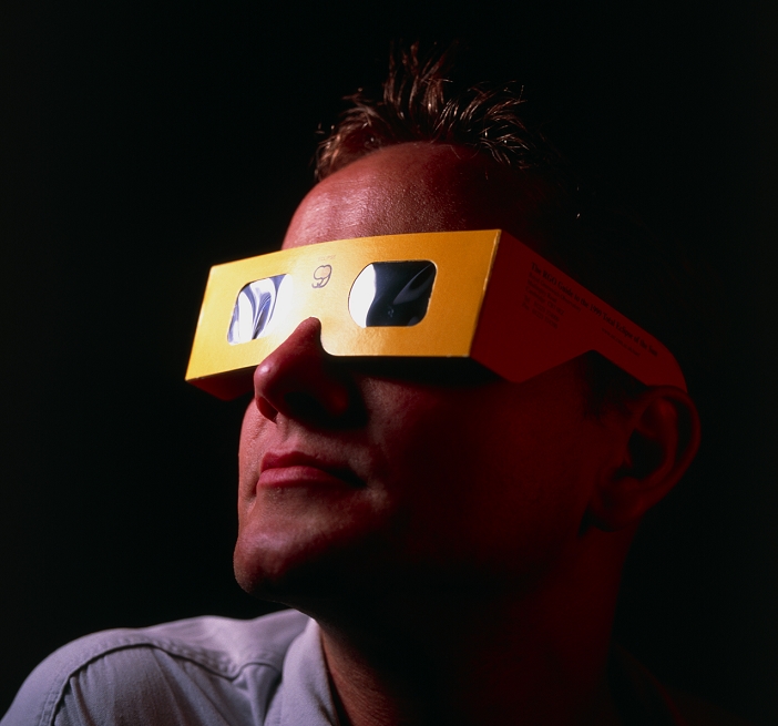 . Solar viewing glasses. Man wearing glasses designed to allow him to view the Sun. The lenses of these glasses are made from mylar coated in aluminium. Mylar is a synthetic polymer. These lenses reduce the sunlight's intensity, making it safe to view the Sun for short periods. This allows the user to observe the Sun, for instance for planetary transits, sunspots or the early stages of a solar eclipse. Viewing the Sun directly can lead to damage to the eyes and even blindness. MODEL RELEASED