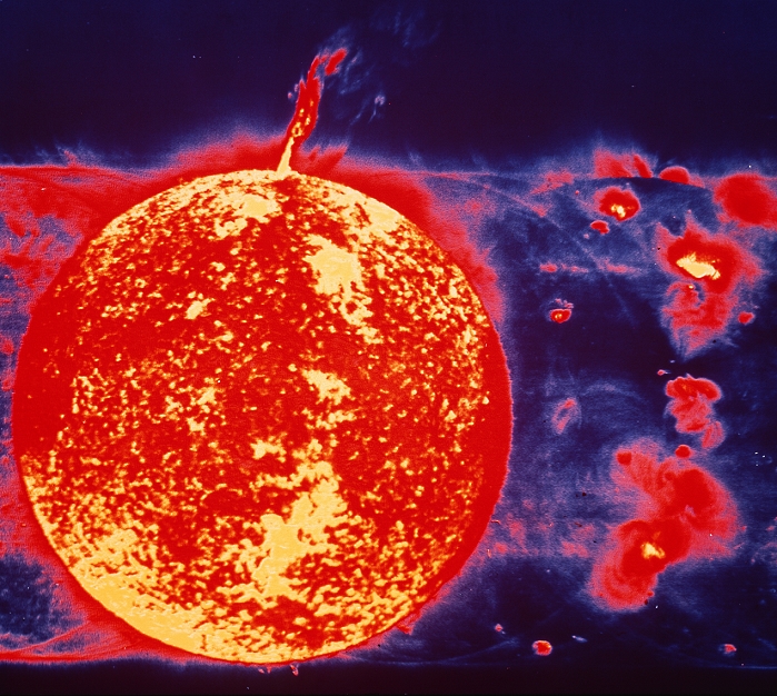 False-colour extreme ultraviolet image of the solar disc & a huge solar prominence, recorded by the Skylab space station in 1973. The disc of the Sun (left) was recorded at the 30.4 nanometre wavelength of radiation from helium atoms stripped of 1 electron. These atoms occur in the lower atmosphere, so the disc shows the clumpy distrib- ution of helium gas just above the Sun's visible surface - along with the prominence projecting half a million km (almost 50 Earth-diameters) at top. The 'ghost' images to left & right of the full disc were recorded at nearby ultraviolet wavelengths & show radiation from other atoms in the solar atmosphere. (More details on request). This picture is Fig. 2.1 in THE NEW ASTRONOMY & is described more fully on page 15 of that book.