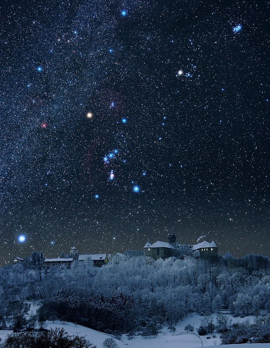 Winter sky. The constellation Orion is at centre. The most prominent feature is the belt of three bright stars in a line. Above and left of the belt is the red supergiant star Betelgeuse (Alpha Orionis). Below and right of the belt is the blue supergiant star Rigel (Beta Orionis). Directly below the belt, the Orion Nebula (M42) is seen as a pink smudge. Near the horizon at lower left is Sirius (Alpha Canis Majoris), the brightest star in the sky. The Pleiades star cluster (M45) is seen at top right. Photographed from Germany.