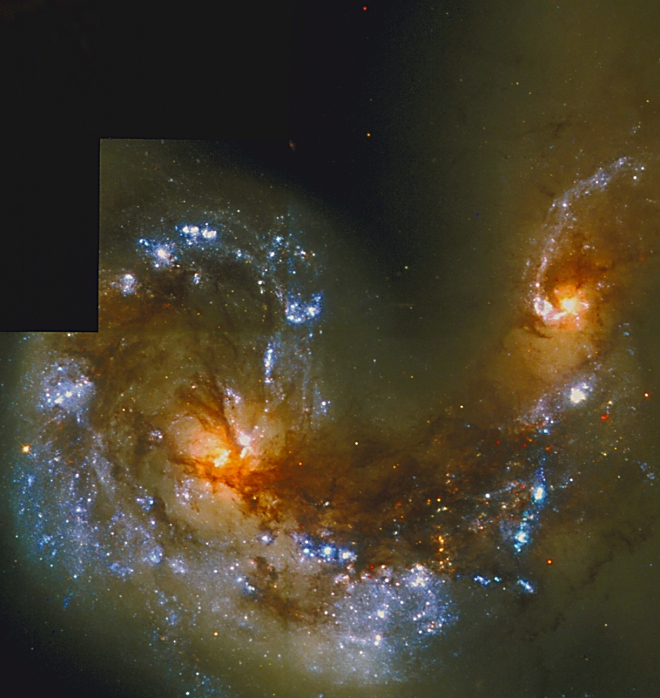 Antennae Galaxies. Hubble Space Telescope image of star birth caused by the interactions of the Antennae Galaxies (NGC 4038/4039). These two spiral galaxies are colliding in the constellation of Corvus at a distance of about 63 million light years from Earth. Their cores (orange, at centre left & upper right) are crossed by dark lanes of dust. Chaotic gas clouds lie between the cores. The creation of over 1000 bright, young star clusters (white/blue) has been triggered by the galaxies' collision. Image taken by Hubble's Wide Field Planetary Camera 2; the smallest visible features are 15 light-years across.