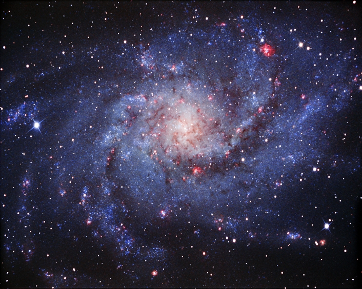 Triangulum Galaxy (M33, NGC 598). Also known as the Pinwheel Galaxy, this spiral galaxy is about 2 million light years away in the constellation Triangulum. It is relatively small, at around 30,000 light years across and is of type Sc, meaning that it has no central bar and has a loosely packed centre and arms. It is part of the Local Group of galaxies that includes our Milky Way Galaxy. The galaxy contains star-forming regions that contain ionized hydrogen gas (red).