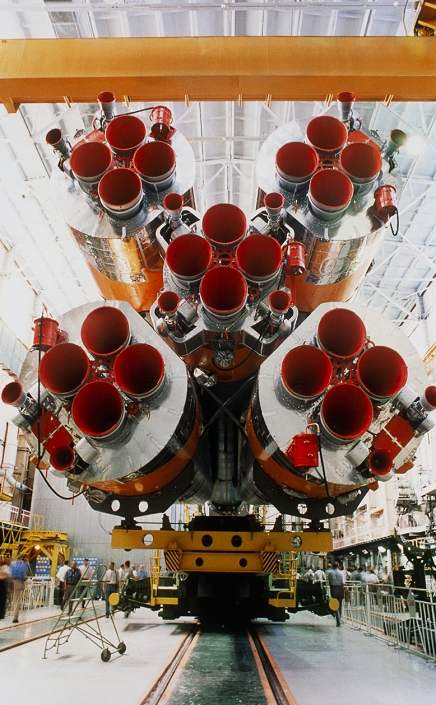 . Soyuz rocket assembly at the launch preparation bay at Baikonur Cosmodrome, Kazakhstan. This bay is where the payload (not seen) is attached to the top of the rocket. The red nozzles are where the exhaust gases emerge from the base of the rocket, launching it on the first stage of a trajectory towards Earth orbit. Four boosters are seen around a core, second stage rocket, which will take over from the boosters when they have exhausted their fuel. The Soyuz rockets are used by Starsem, a French-Russian consortium that provides commercial launch services for payloads such as satellites. Photographed in July 2000. MODEL RELEASED