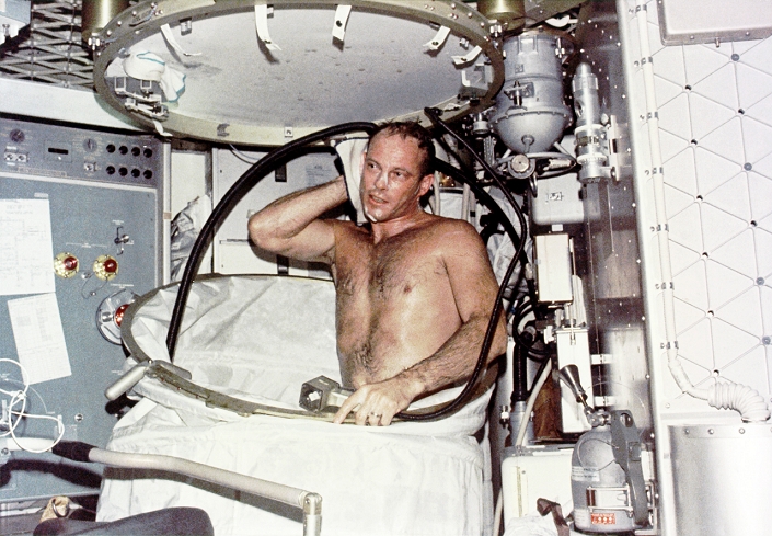 Showering on Skylab. Astronaut Jack R Lousma taking a shower on board the orbiting Skylab space station. Showering in the microgravity conditions experienced in orbit required specialised equipment. The water was pumped both into and out of the curtained cubicle. Lousma, along with Alan Bean and Owen K Garriott, spent 59 days in orbit from 28th July 1973, and conducted numerous scientific experiments.