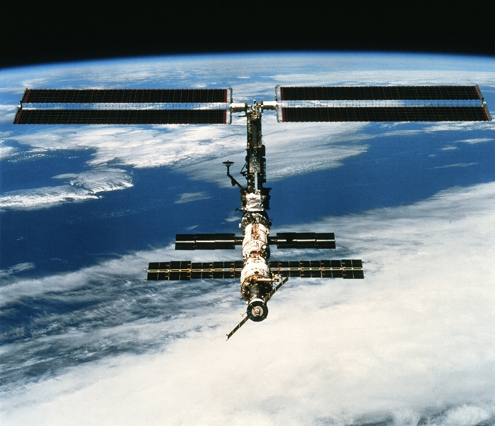 International space station (ISS) seen from the Space Shuttle Endeavour after undocking. A Soyuz spacecraft (black, lower centre) is docked to the Zvezda Service Module, with the Zarya or Functional Cargo Block (FGB, also lower centre) and the Unity node (grey, centre) also seen. During Endeavour's mission (STS-97, 30 November to 11 December 2000), the ISS's 73-metre solar arrays (upper frame) were attached and unfolded. The ISS is a joint effort between NASA, the European Space Agency, the Russian space agency, Canada, Japan and Brazil. The space station has been manned since late 2000. Photographed on December 9.