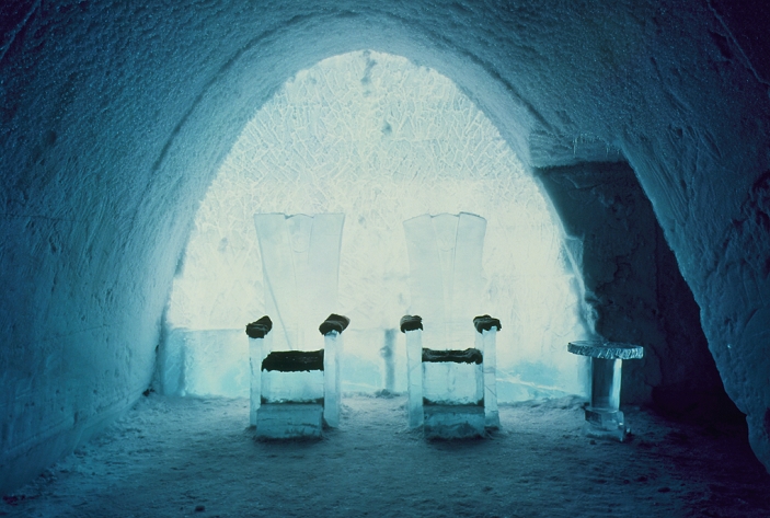 Ice Hotel. Ice thrones made for the Swedish King and Queen for the year 2000 New Year celebrations at the Ice Hotel, a hotel made entirely from snow and ice. The hotel is the world's largest igloo, and lies within the Arctic Circle in Jukkasjarvi, Sweden. It is made every winter by spraying 30,000 tonnes of snow onto moulds which are removed once the snow has compacted. 10,000 tonnes of ice are also used. The hotel sleeps over 100 guests on ice beds. Visitors keep warm in their sleeping bags despite temperatures that reach -9 degrees Celsius. Guests can visit the ice exhibition hall, sauna, cinema or chapel, as well as drink from ice glasses in the ice bar. The hotel melts every May.