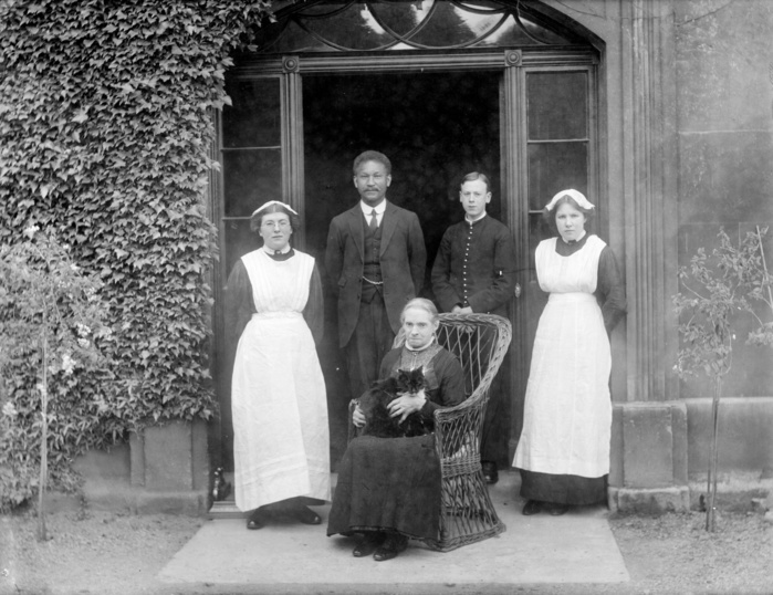 King s School House, College Green, Gloucester, Gloucestershire, 1860 1922. Creator: Unknown. King s School House, College Green, Gloucester, Gloucestershire, 1860 1922. A group of domestic servants posed outside the doorway of King s School House. The housekeeper is holding her cat.