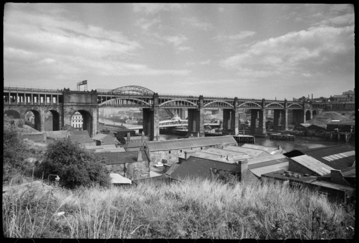 High Level Bridge, Newcastle Upon Tyne, Tyne  amp  Wear, c1955 c1980. Creator: Ursula Clark. High Level Bridge, Newcastle Upon Tyne, Tyne  Wear, c1955 c1980. A view of the High Level Bridge spanning the River Tyne, with domestic and industrial buildings in the foreground, and a view of the south bank of the river in the background, seen from north west of the bridge, at a high vantage. The bridge is a combined road and railway bridge, built by Robert Stephenson in 1849 with cast iron and ashlar, with the road on the lower beam, with segmental iron arches and beams supporting the railway above, as well as the five ashlar piers across the river. At the northern end of the bridge is a large round arch, and the southern end is supported by an iron cage on four iron columns. Behind the bridge the Swing Bridge and New Tyne Bridge can just be seen, as well as industrial buildings on both sides of the river.
