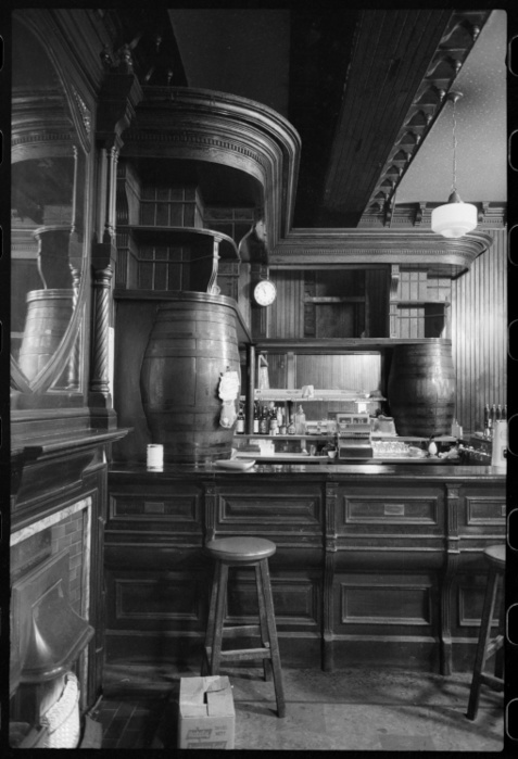 Bar of the Royal Turk s Head Hotel, 73 Grey Street, Newcastle upon Tyne, c1955 c1980. Creator: Ursula Clark. Bar of the Royal Turk s Head Hotel, 73 Grey Street, Newcastle upon Tyne, c1955 c1980. The building that the Turks Head was situated had been built for Richard Grainger in c1837, and has been used as a location for houses, shops and a hotel. The image shows a curved bar in the corner of the room, with shelving built along the walls and supported at each end by barrels. There are bar stools on the customer side, and a mirror above a fireplace in the foreground.
