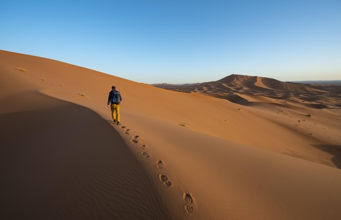 Young man walks on a sand dune, dune landscape Erg Chebbi, Merzouga, Sahara, Morocco, Africa, Photo by Mara Brandl